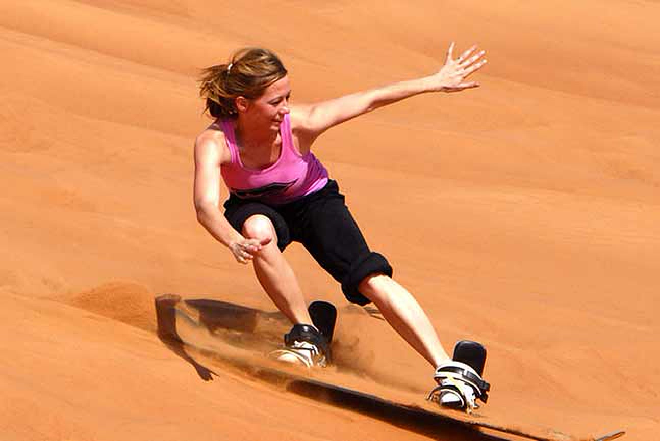 Woman sandboarding down a dune
