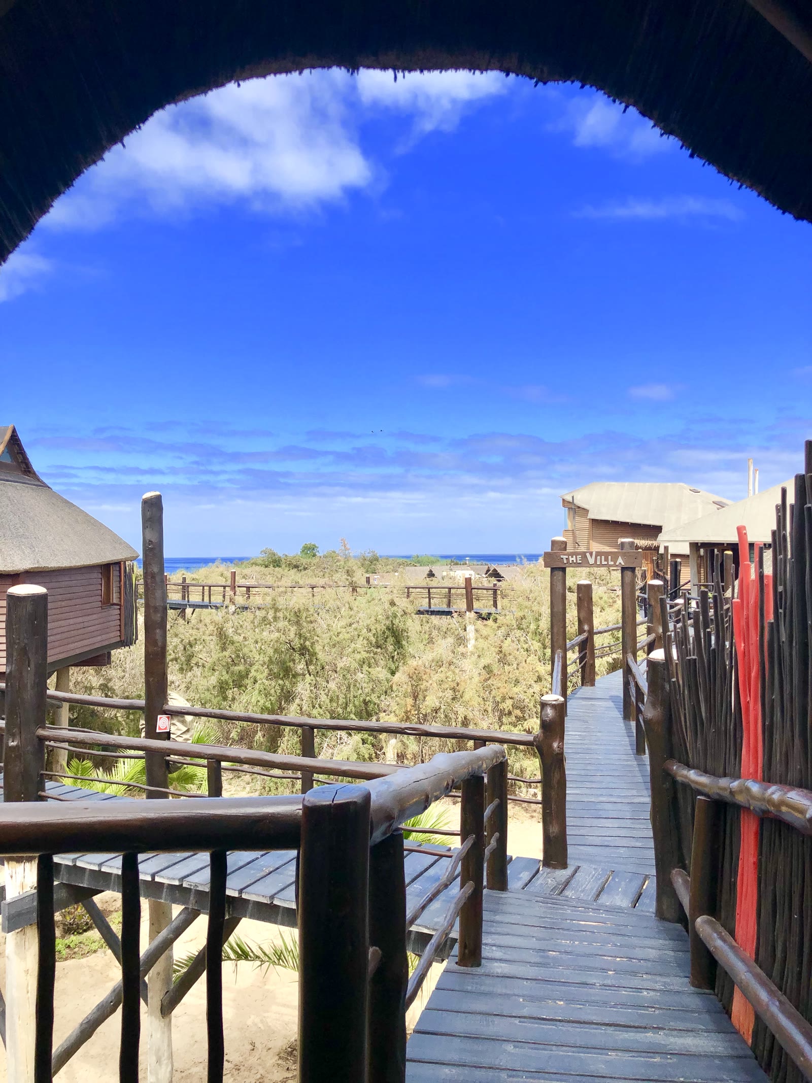 Raised walkway from a bungalow toward The Villa and ocean