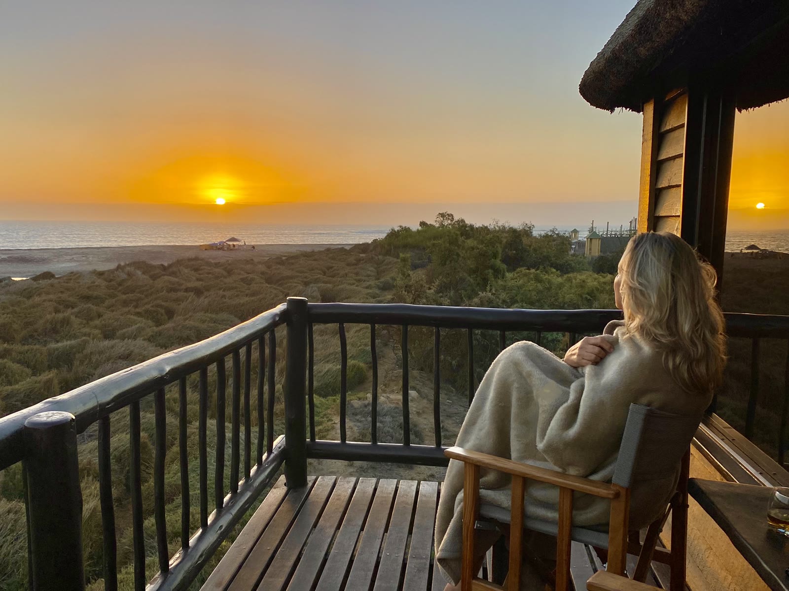 Guest enjoying sunset from a private Lagoon Bungalow balcony